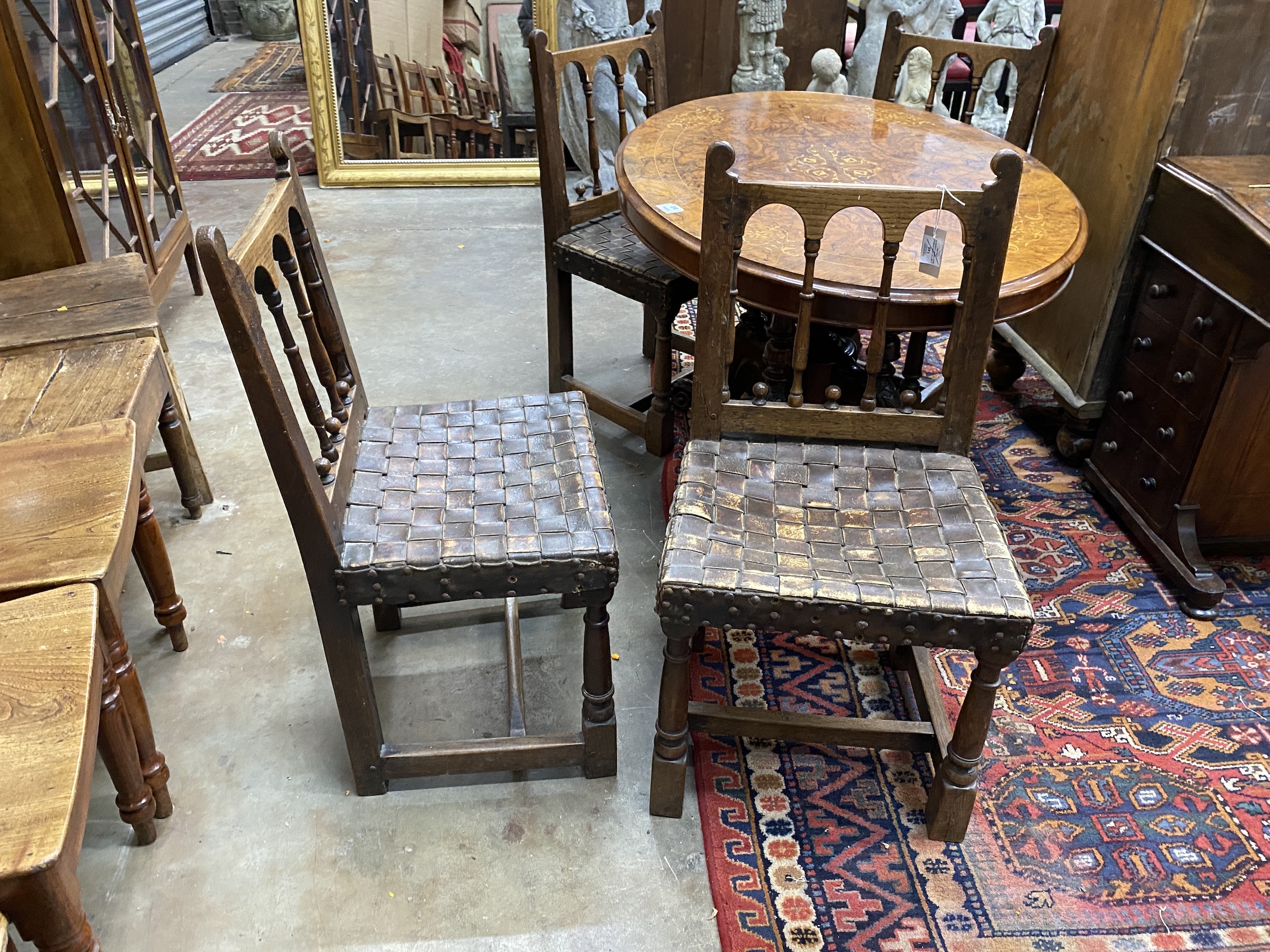 A set of four spindle back dining chairs with leather strapwork seats